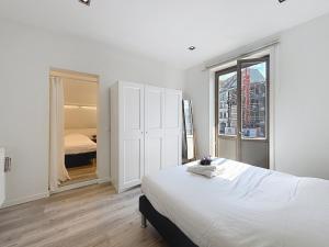 a white bedroom with a large bed and a window at ons kotje in De Panne