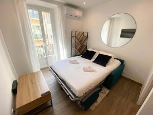 Un dormitorio con una cama con un espejo en la pared. en Studio calme et central avec clim, en Niza