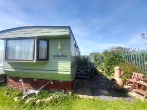 a green caravan sitting in the grass in a yard at 254 Bryn y Mor in Tywyn