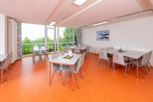 an empty room with tables and chairs and windows at Jugendherberge Hohenstaufen in Göppingen