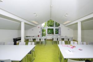 an empty classroom with white tables and chairs at Jugendherberge Hohenstaufen in Göppingen