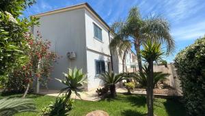 una casa bianca con palme nel cortile di Mare Nostrum Apartment a Marina di Ragusa