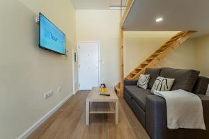 ein Wohnzimmer mit einem Sofa und einem Fernseher an der Wand in der Unterkunft Close to Everything Your Oporto Terrace PRM 1T in Porto