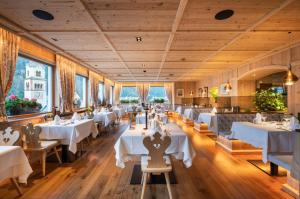 a restaurant with white tables and chairs at Hotel Platz in Ortisei