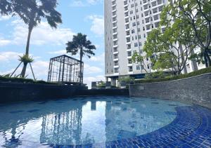 ein Schwimmbad vor einem hohen Gebäude in der Unterkunft Urban Chic Studio at Amor Apartment in Pakuwon City Mall, East Surabaya by Le Ciel Hospitality in Surabaya