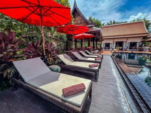 a row of chairs with umbrellas next to a pool at Baan Thai Lanta Resort in Ko Lanta