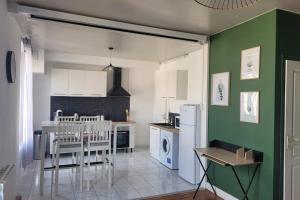 a kitchen with green walls and a table and chairs at La rétro- séance in Soissons