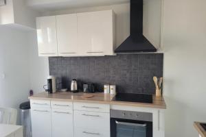 a kitchen with white cabinets and a stove top oven at La rétro- séance in Soissons