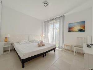a white bedroom with a bed and a window at T3 lumineux avec jardin, parking et piscine in Puget-sur Argens