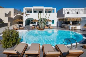 a pool with chaise lounge chairs next to a building at Nissia Beach Apartments & Suites in Kamari