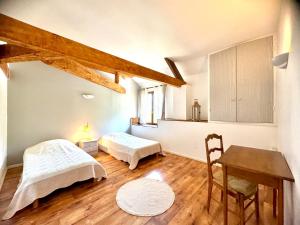 a room with two beds and a desk and a table at Grange authentique avec vue, piscine chauffée et Wifi in Daglan +57 photos