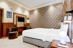 a bedroom with a large white bed and a television at Palette by CheckIn Patliputra Colony Formerly The Aurum in Patna
