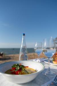 une table avec une assiette de nourriture et des verres à vin dans l'établissement Hôtel de la Plage - Ronce-les-bains, à Ronce-les-Bains 18 autres photos