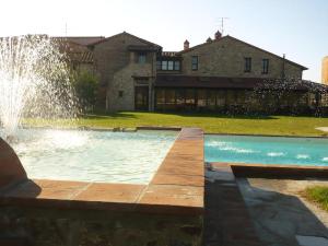 a swimming pool with a fountain in front of a house at Kormoransee Ferien in Pucciarelli