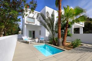 a white house with a swimming pool and palm trees at Blanco Hotel Formentera in Es Pujols