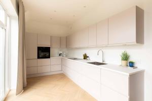 a kitchen with white cabinets and a sink at Stunning Premium Apartment with Private Rooftop in Copenhagen