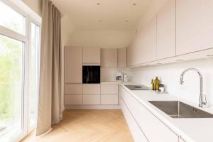 a kitchen with white cabinets and a large window at Stunning Premium Apartment with Private Rooftop in Copenhagen