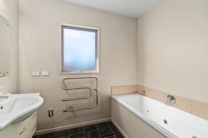 ein weißes Badezimmer mit Waschbecken, Badewanne und Fenster in der Unterkunft Hikuwai Family Retreat - Albert Town Holiday Home in Wanaka + 14 Fotos