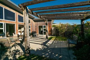 eine hölzerne Pergola mit Stühlen und Tischen auf einer Terrasse in der Unterkunft Hikuwai Family Retreat - Albert Town Holiday Home in Wanaka