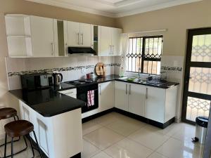 a kitchen with white cabinets and black counter tops at 142Woodlands in Mbabane