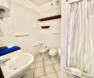 a white bathroom with a toilet and a sink at Luxury apartment Ginepro sea view with common swimming pool just 50 mt from the beach in Golfo Aranci