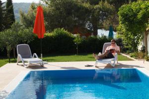 a woman sitting in a chair next to a swimming pool at Villa Marin in Sutomišćica