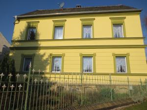 ein gelbes Haus mit einem Zaun davor in der Unterkunft Ferienwohnung Creutzer in Gottscheina