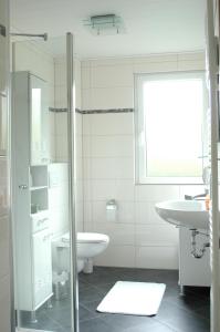 a white bathroom with a sink and a toilet at Ferienhaus Mit Indoorpool, Garten Und Partyraum in Geestland