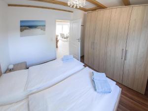 a white bedroom with two beds and a closet at Ferienhaus Mit Atemberaubendem Blick Auf Den See in Wiefelstede +12 photos