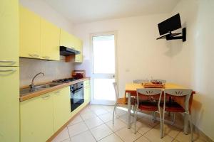 a kitchen with yellow cabinets and a table with chairs at Ferienwohnung In Torre Mozza Mit Terrasse in Torre Mozza