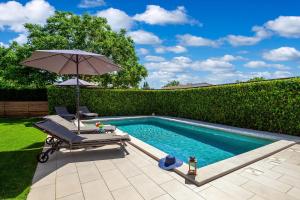 a swimming pool with an umbrella and a chair and an umbrella at Ferienhaus Casa Mia Mit Privatem Pool in Barban