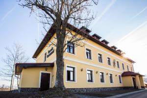 a yellow building with a tree in front of it at Penzión Altmayer in Banská Štiavnica