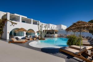 a swimming pool with chaise lounge chairs and umbrellas at Nissia Beach Apartments & Suites in Kamari