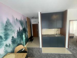 a kitchen with a painting of trees on the wall at TRITA SK - Apartmán Tatragolf C303 in Veľká Lomnica