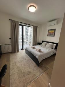 a bedroom with a large bed and a large window at BW Simfonia Apartman 407-whit free garage parking in Belgrade