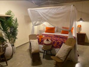 a bedroom with a canopy bed and two chairs at Toubacouta Lodges in Toubakouta