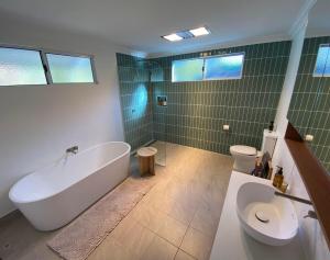 a bathroom with a tub and a toilet and green tiles at Mayfield House Collie in Collie +15 photos