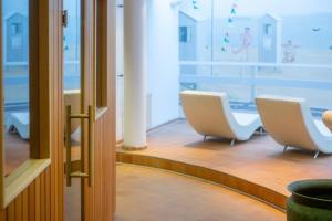 a waiting room with two white chairs in front of a window at Strandhotel Sylt Westerland in Westerland