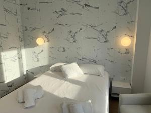 una camera con letto bianco e parete in marmo di Design and style next to Playa de Valencia a Valencia