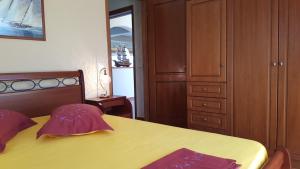 a bedroom with a yellow bed and a wooden cabinet at Villa Politimi at Aegina in Mesargos