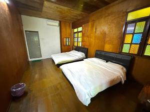 バリック・プラウにあるQuadruple Traditional Wooden GuestHouseの木製の壁と窓のある部屋にベッドが2つある