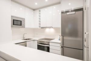 Una cocina con gabinetes blancos y un refrigerador de acero inoxidable. en Apartarent 1500 - Apartamento Letassi, en Baqueira Beret 8 fotos más