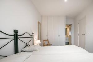 1 dormitorio con cama blanca y pared blanca en Apartarent 1500 - Apartamento Letassi, en Baqueira Beret