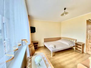 a small room with a bed and a table and a window at Podlesie in Ostrowo