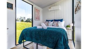 a bedroom with a bed and a large window at Gold Fields by Tiny Away in Ross Creek