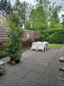 a patio with two white benches and a fence at Chalet "Uit Zicht" in Putten