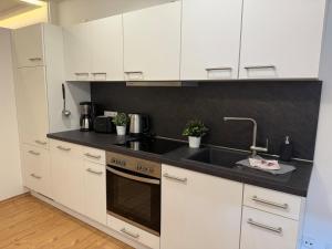 a kitchen with white cabinets and a sink at K38 Mühlgrabenblick by Selected Rooms in Eisenach +9 photos