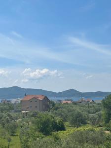 ein Gebäude auf einem Feld mit Bäumen und einem Gewässer in der Unterkunft Apartments Marina in Sukošan