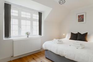 a white bedroom with a large bed and a window at Duplex Redhill town centre apartment by Livingo Stays in Redhill