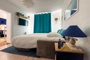a bedroom with a bed and a blue curtain at Ohana in Deauville
